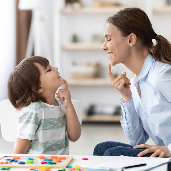 Young child and therapist smiling during a speech session