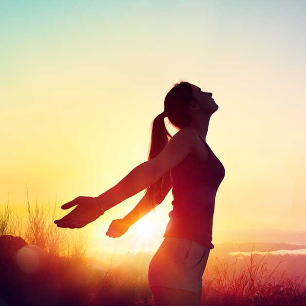 Woman with arms open at sunset