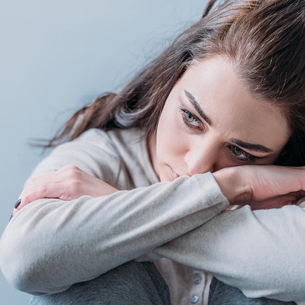 Woman resting her chin on folded arms, looking thoughtful